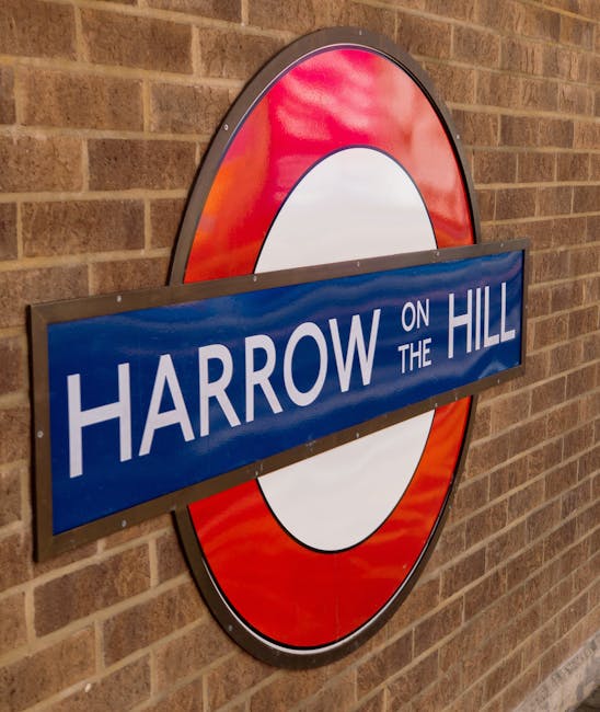 A close-up photograph of a classic London Underground sign mounted on a brick wall near Harrow on the Hill station. The sign features the iconic red circle with a white inner ring, and a horizontally 